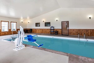Una piscina interior con una silla de salvavidas, un panel de pared de madera y una puerta.