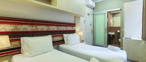 A hotel room with two beds, a bathroom, and a wardrobe.