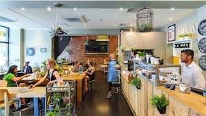 A modern cafe with wooden tables, brick walls, and a variety of plants. - Best Western Melbourne City (Melbourne)