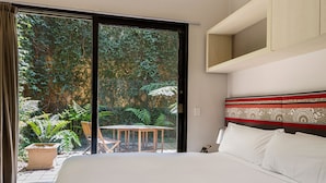 A bedroom with a large bed, a view of a garden through a sliding door, and a small table with chairs outside. - Best Western Melbourne City (Melbourne)