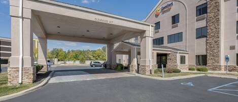A Comfort Suites hotel entrance with a covered parking area, clear signage, and a handicap parking space.