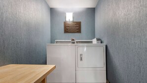 A guest laundry area with a sign, two washing machines, and a wooden table.