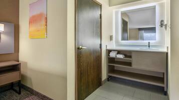 Un baño de hotel con puerta de madera, un lavabo con espejo y un perchero para toallas.