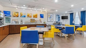 A modern dining area with a counter, seating, and artwork on the walls.