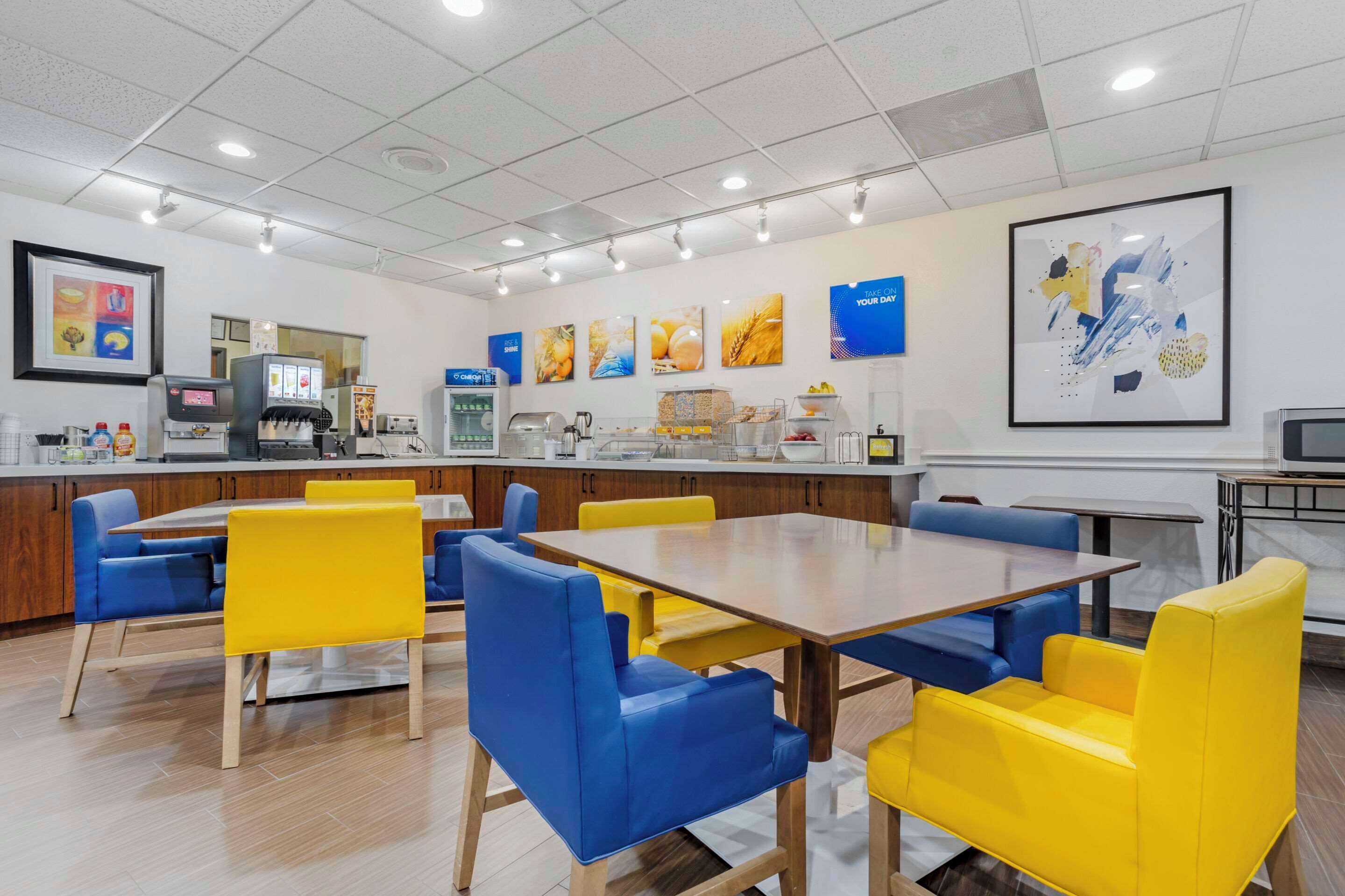 A modern dining area with a long wooden table and blue and yellow chairs.