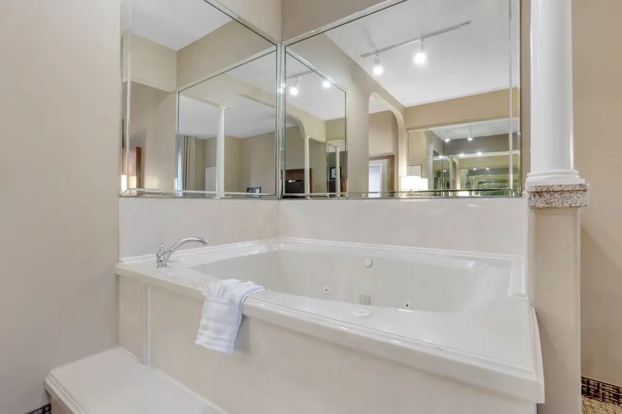 Un baño moderno con una bañera grande, un lavamanos y un espejo sobre la bañera.