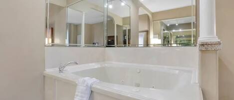 Un baño moderno con una bañera grande, un lavamanos y un espejo sobre la bañera.