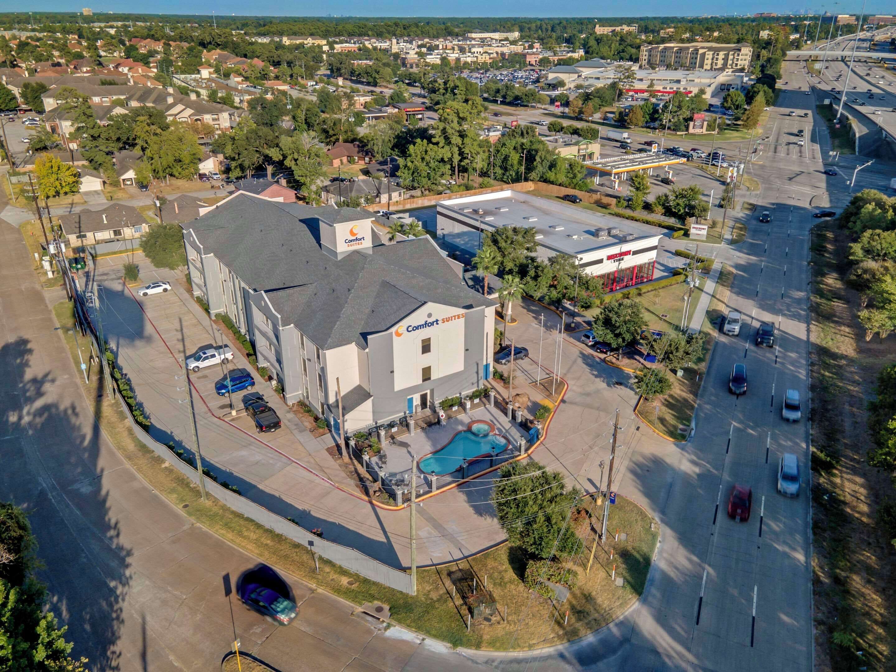 A hotel with a swimming pool, located at a corner with a parking lot.