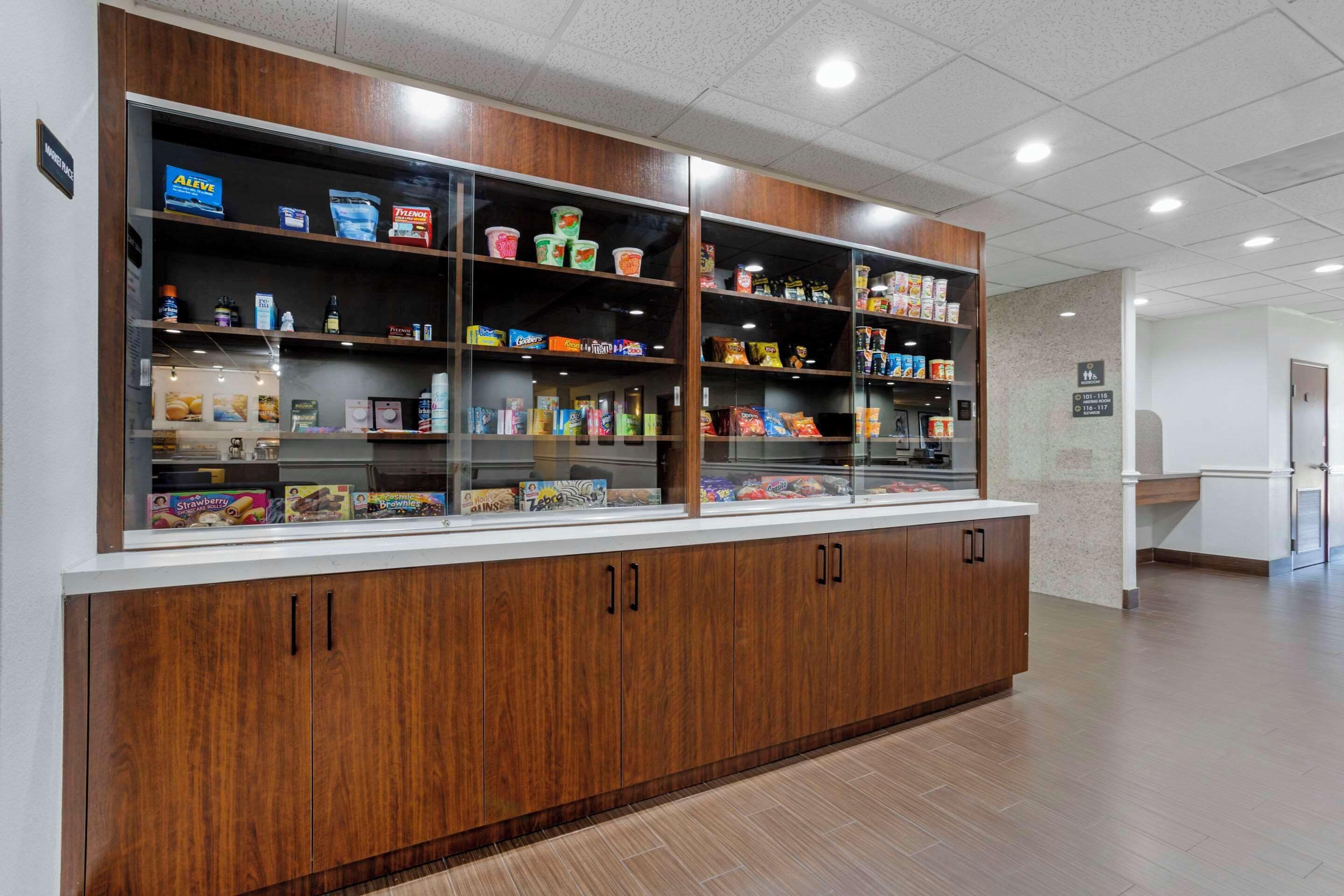 A snack bar with wooden cabinets and glass display cases containing various food items.