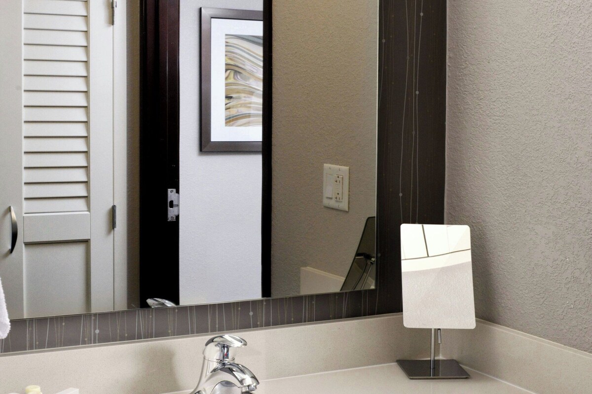 A bathroom with a white sink, a mirror, and a towel rack.