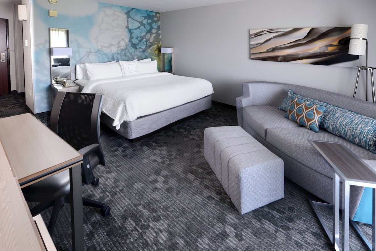 A hotel room with a large bed, a sofa, a desk, and a chair.