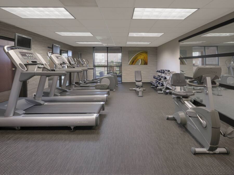 A gym with treadmills, stationary bikes, and dumbbells.