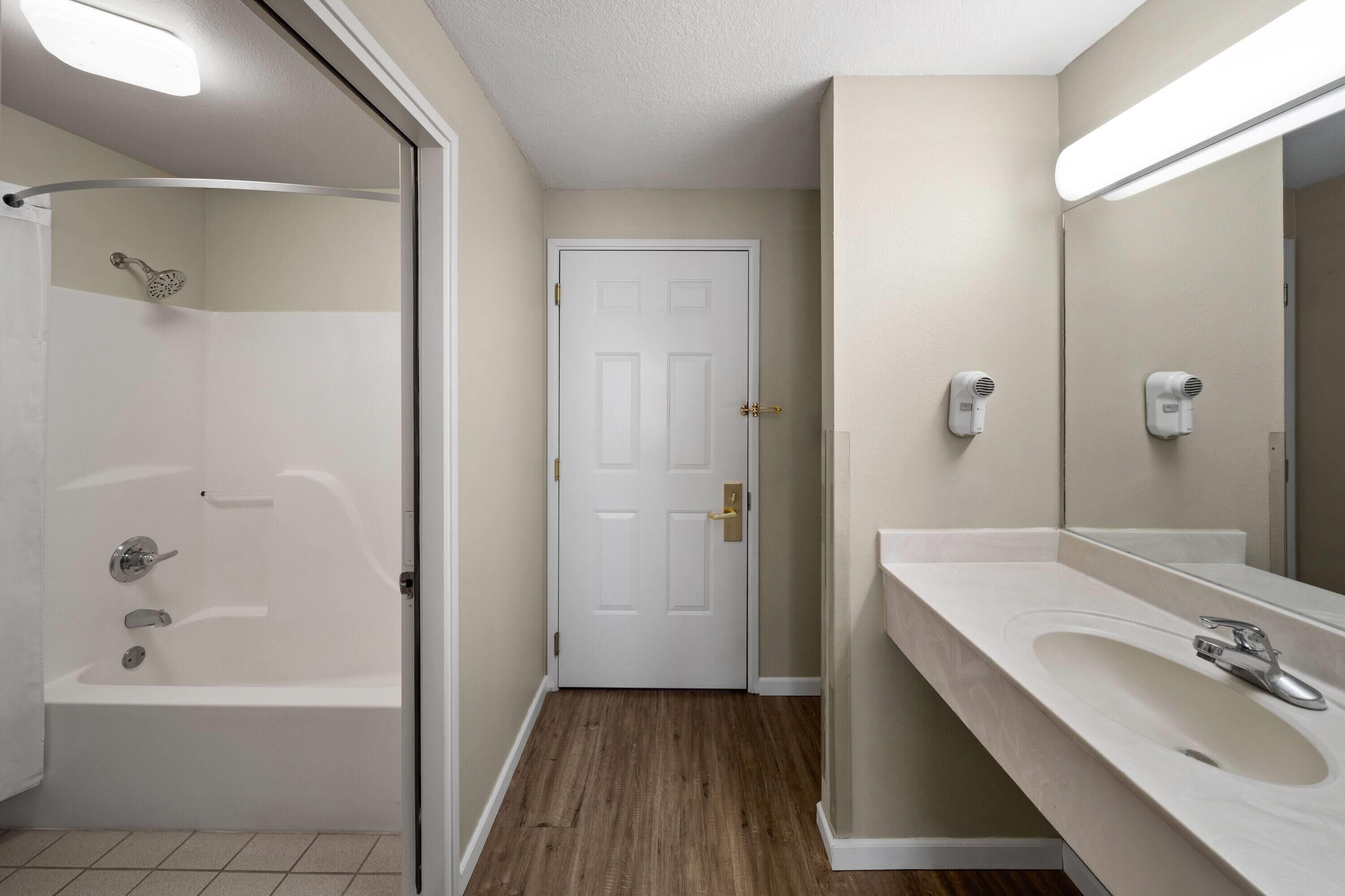 A bathroom with a bathtub, a shower, a sink, and a door.