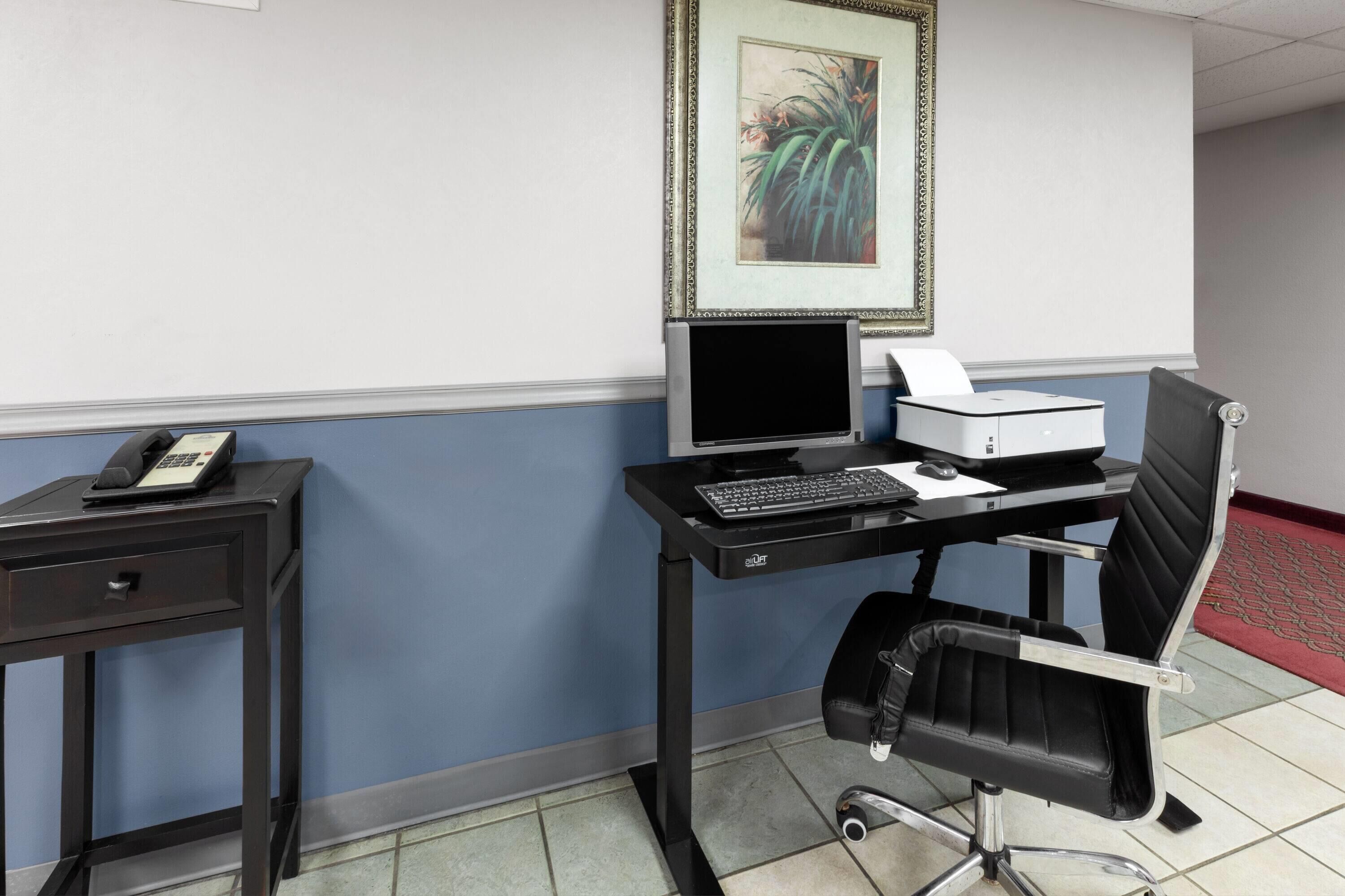 A modern office setup with a desk, computer, chair, and a telephone on a side table.