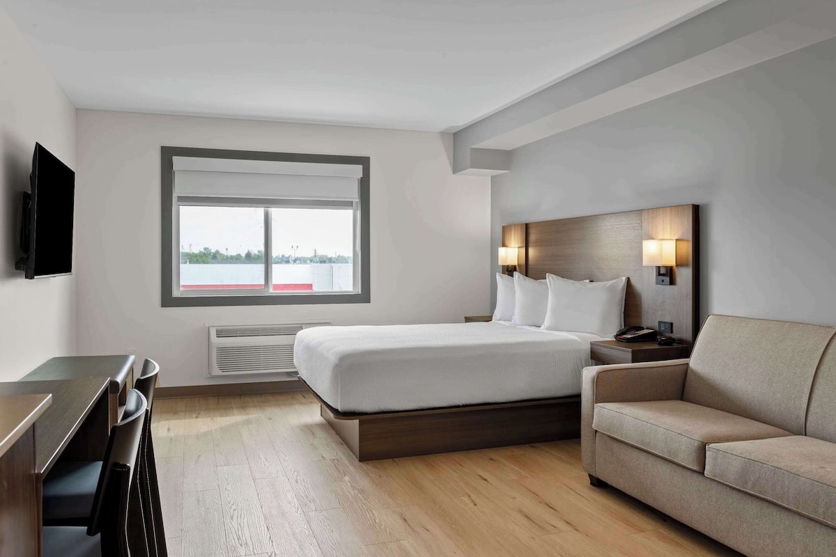 Ein modernes Hotelzimmer mit Bett, einer Couch, einem Schreibtisch und einem Fernseher.
