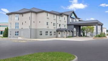 A hotel with a modern design, featuring a large parking lot and a covered entrance.