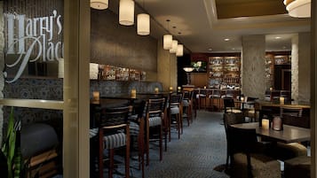 Un interior de restaurante con zona de bar, diferentes opciones de asientos como cabinas y mesas, y una alfombra estampada.