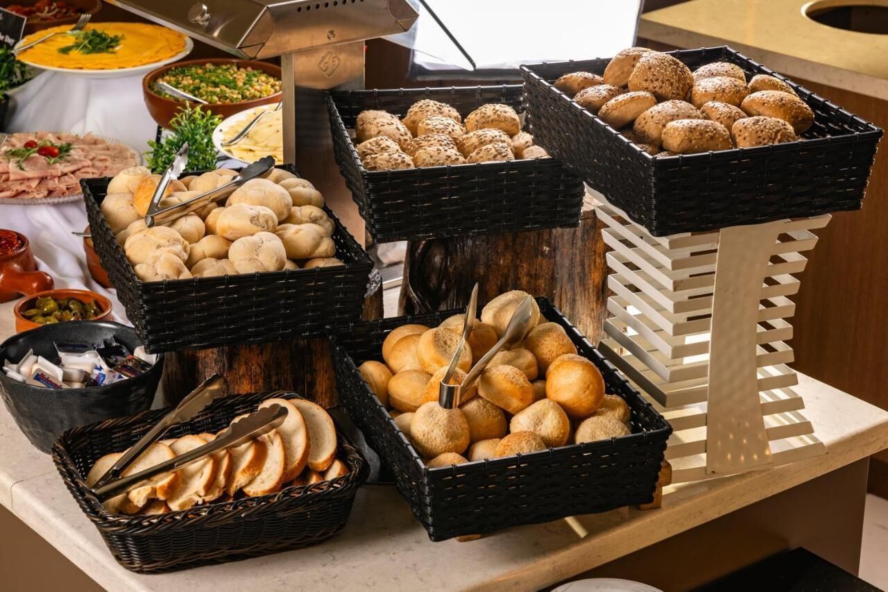 A buffet table with various food items including bread, rolls, and other baked goods.
