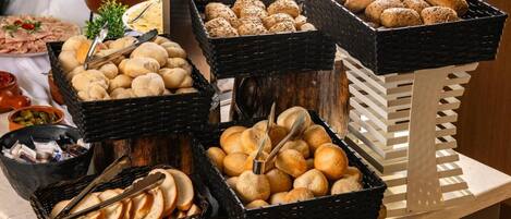 A buffet table with various food items including bread, rolls, and other baked goods.