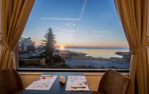A table with menus and a view of the sunset over the sea. -  Vivaldi Malta (St. Julian's)