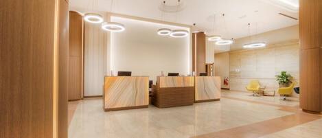 A modern reception area with marble reception desks, a clean tiled floor, and a minimalist design.