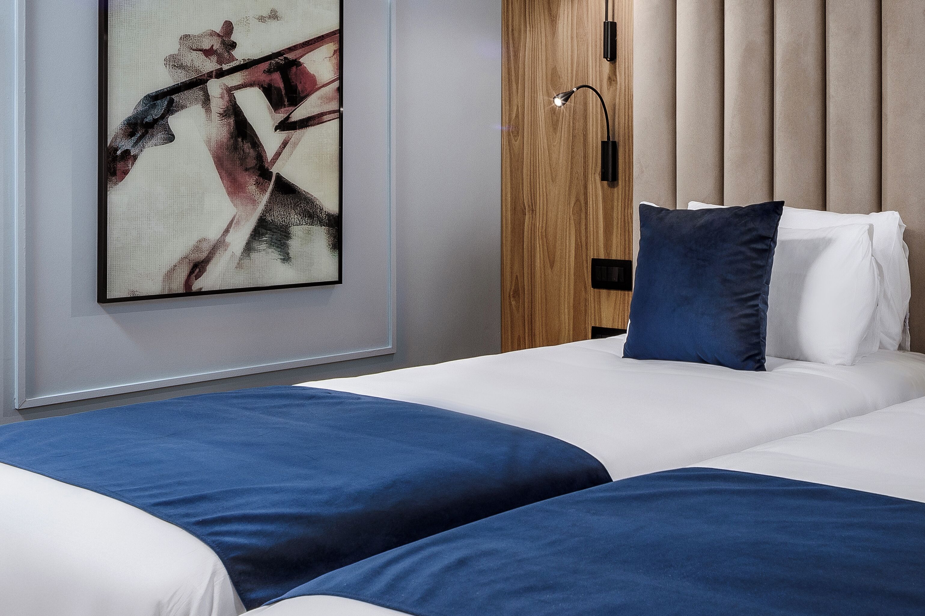 Una habitación de hotel con una cama, un armario de madera y un cuadro en la pared.
