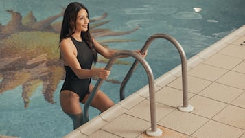 Una piscina al aire libre, sombrillas, sillones reclinables de piscina