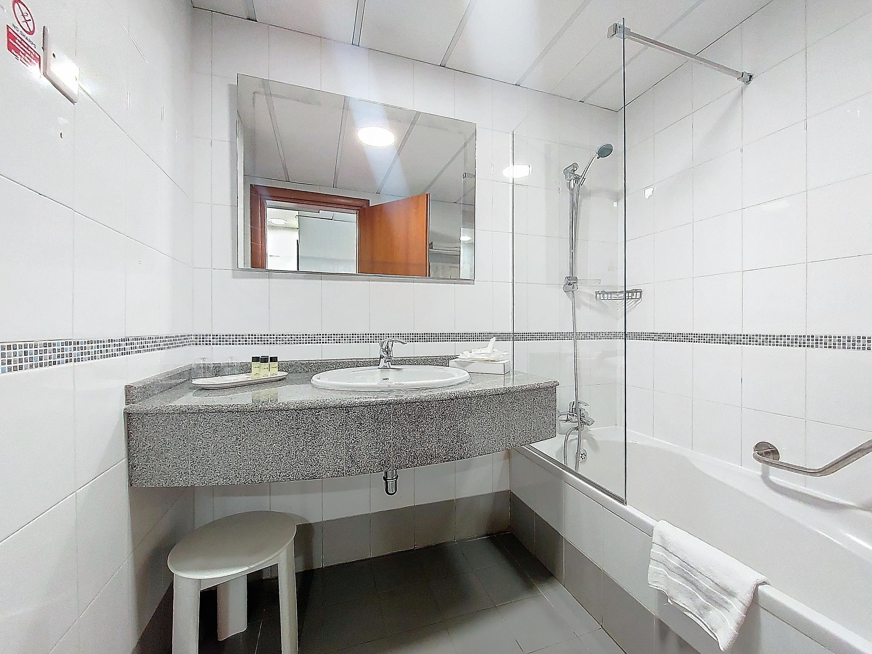 A bathroom with a sink, mirror, shower, and toilet.