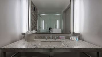 A modern bathroom with a granite countertop, a sink, and a large mirror.