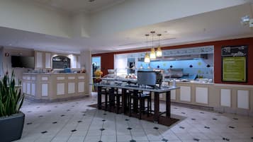 Uma cozinha moderna com balcão, uma tela grande e uma área de estar com uma mesa central.