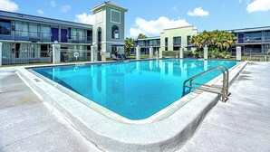 Una piscina rettangolare con una scala in metallo, circondata da un solarium in cemento.