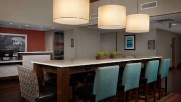 A hotel reception area with a long counter, several chairs, and hanging lamps.