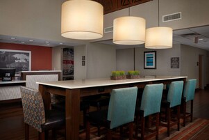A hotel reception area with a long counter, several chairs, and hanging lamps.