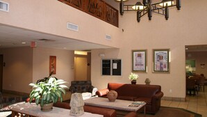 A lobby with a brown leather sofa, a table with a potted plant, and a chandelier. - Hampton Inn Phoenix/Glendale/Peoria (Peoria)