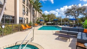 A poolside area with lounge chairs, umbrellas, and a pool.