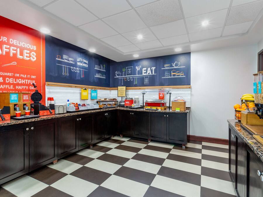 Una cocina con equipo para hacer gofres, piso de cuadros y una pared con texto e ilustraciones sobre gofres.