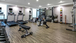 A gym with treadmills, elliptical machines, a stationary bike, and various weights.