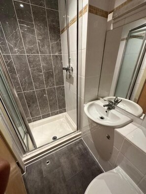 A bathroom with a glass-enclosed shower, a sink, and a toilet. - Berkeley Court Hotel (London)