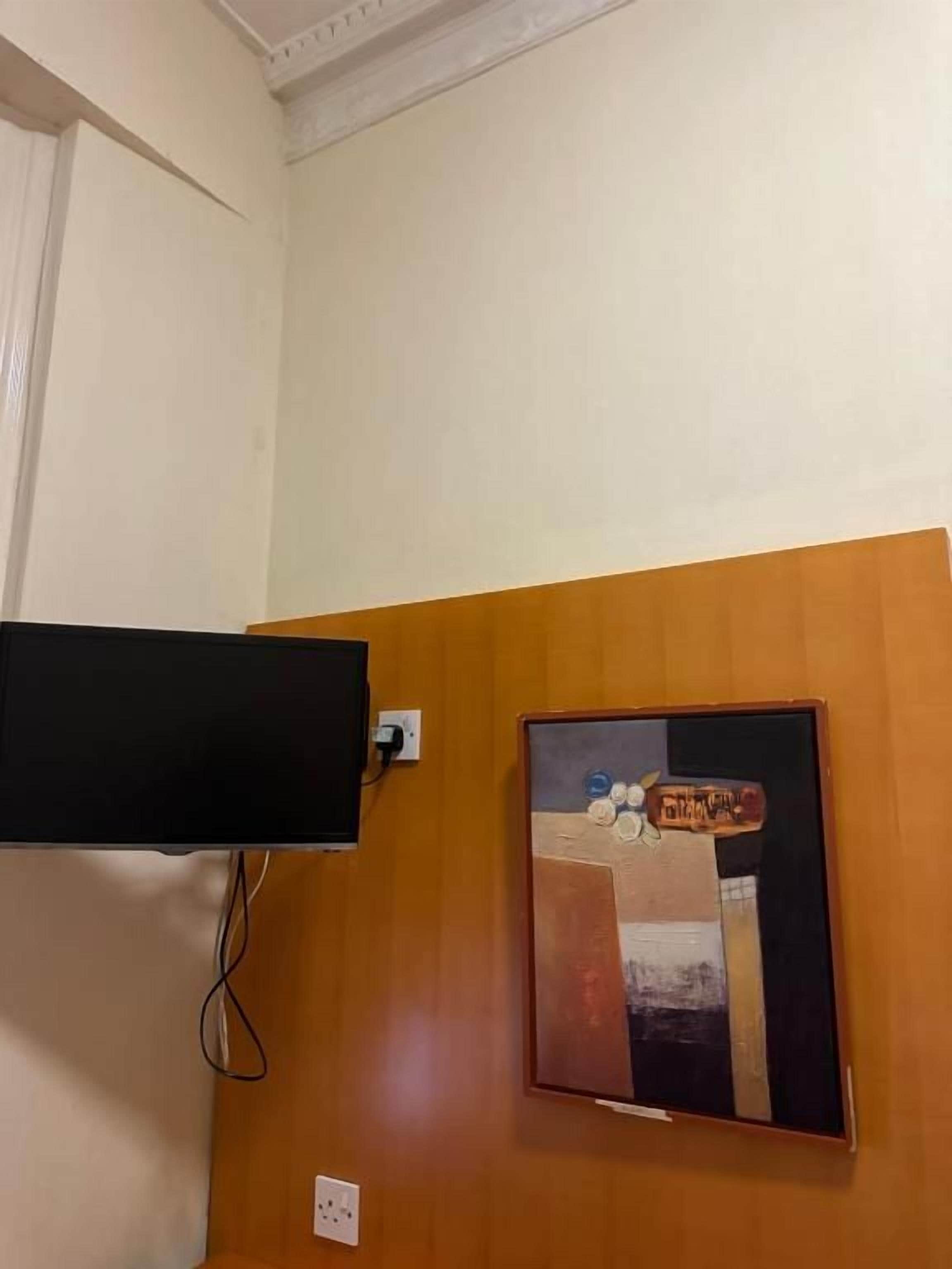 A room with a mounted television on the wall and a framed artwork below it.