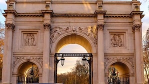 Un arco de piedra ornamentado con esculturas clásicas y un paso central.