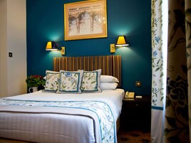 A hotel room with a bed, a nightstand, a lamp, and a framed picture on the wall.