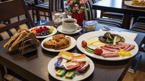 A breakfast table with croissants, fruit, cheese, and ham. - London Lodge Hotel (London)
