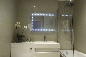 Een moderne badkamer met een wastafel, spiegel en douche.