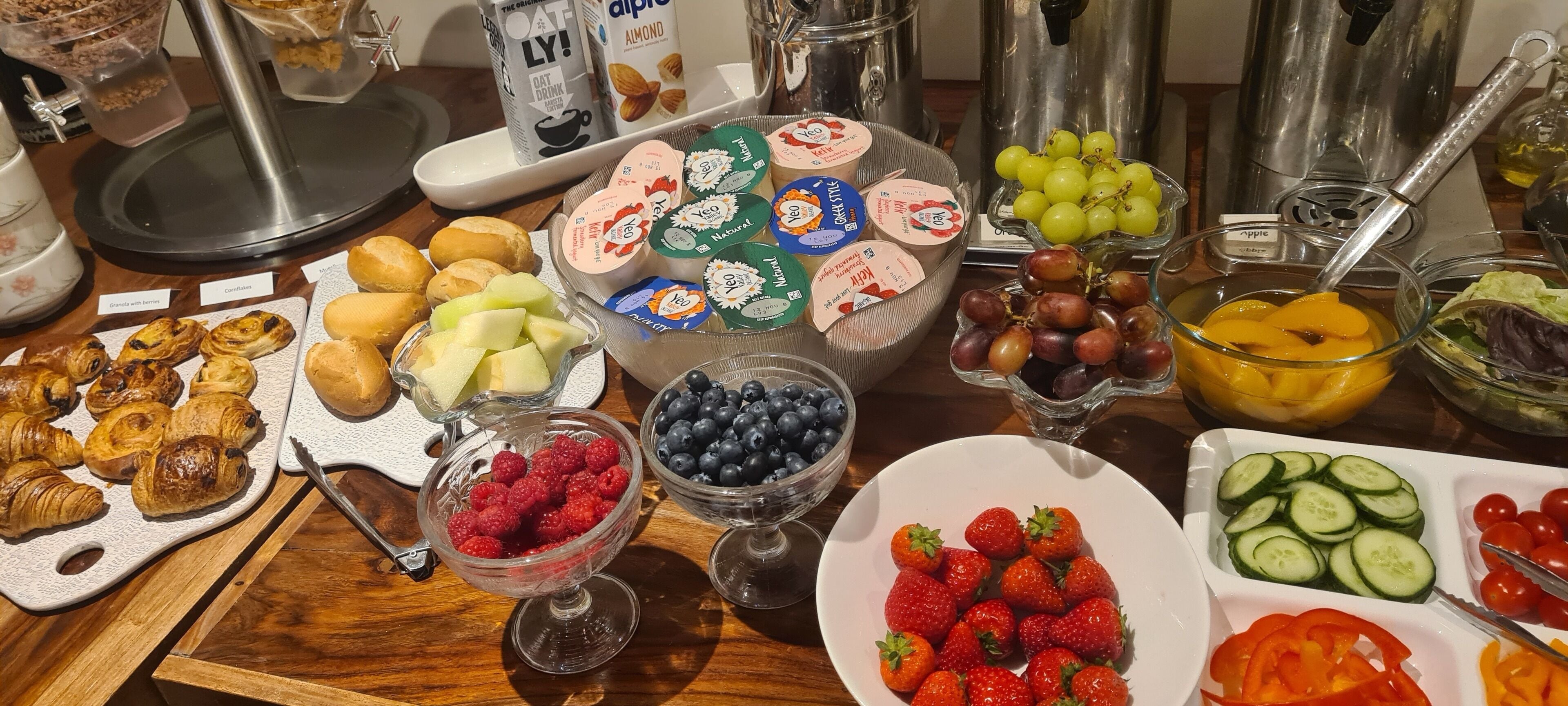 A breakfast buffet with various food items including pastries, fruits, and yogurt parfaits.