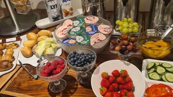 A breakfast buffet with various food items including pastries, fruits, and yogurt parfaits.