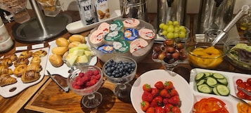 A breakfast buffet with various food items including pastries, fruits, and yogurt parfaits.
