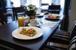 Ein Frühstückstisch mit Toast, Avocado, Ei, Orangensaft und einer Tasse Kaffee.