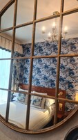 Ein Schlafzimmer mit einem Bett, einer Chandelüster und floralem Wandpapier.