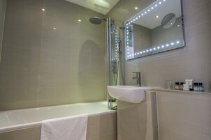 Ein modernes Badezimmer mit Badewanne, einer behinderten-freundlichen Dusche und einem Waschtisch mit Spiegel.