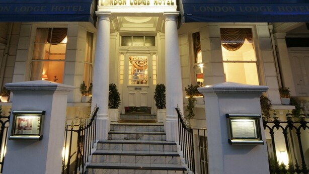 The entrance of the London Lodge Hotel with a grand facade, large columns, and a well-lit entrance. - London Lodge Hotel (London)